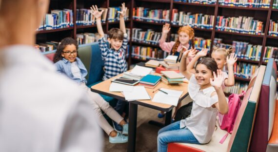 kids raising hands in library