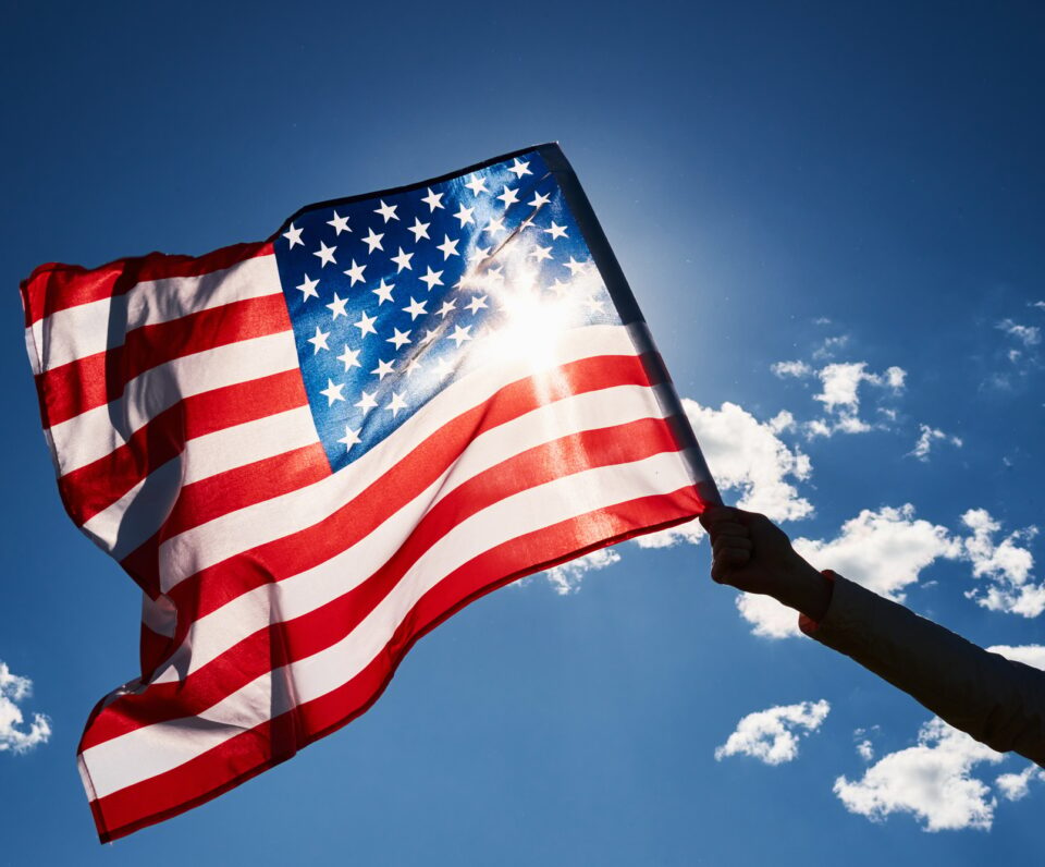 Waving usa flag in hand against blue sky